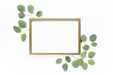 Square gold frame decorated with green eucalyptus leaves, twigs, floral pattern on a white background. The apartment lay, top view. Floral frame. Frame of flowers.