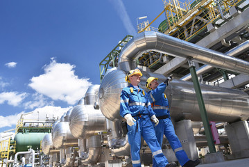 Arbeiter in einer Raffinerie - im Hintergrund Anlage zur Produktion von Treibstoff aus Erdöl -...
