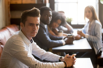 Diverse people looking at thoughtful frustrated man in cafe, sad misunderstood guy feels offended...