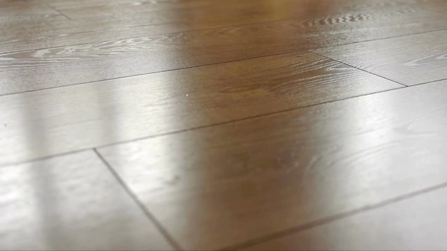 The camera moves along the floor, covered with laminated parquet with a brown wooden texture