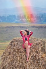 A model in a bright red dress sits on a hay