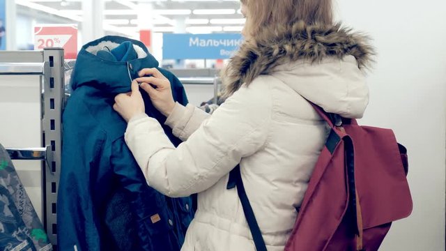 Female Shopping For Sportswear In Sport Clothing Store Choosing jacket.