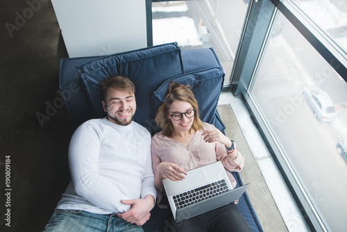 Positive Office Workers Lie On The Sofa Bed Window With A Laptop