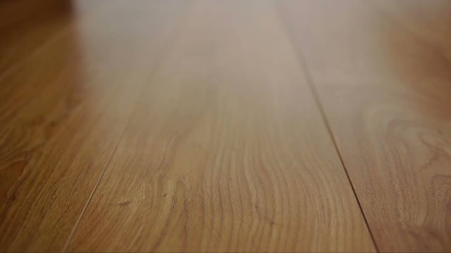 The camera moves along the floor, covered with laminated parquet with a brown wooden texture