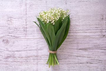 A bouquet of lilies of the valley on a wooden background. View from above