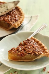 Close up of homemade Classic Pecan pie and a a slice on plate, selective focus