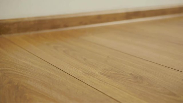 The camera moves along the floor, covered with laminated parquet with a brown wooden texture