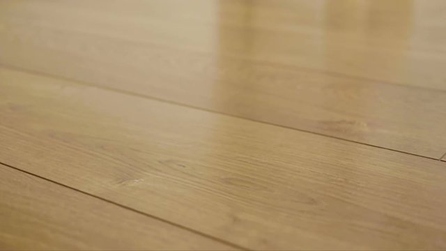 The camera moves along the floor, covered with laminated parquet with a brown wooden texture