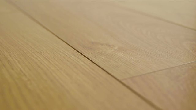 The camera moves along the floor, covered with laminated parquet with a brown wooden texture