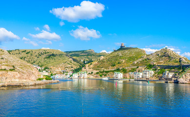 Private houses on the shore of the Balaklava bay, the ruins of the ancient Genoese fortress Cembalo. Balaklava, Crimea, Russia