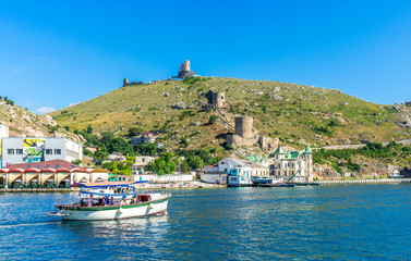 Fototapeta na wymiar Balaklava Bay and the ruins of the ancient fortress Cembalo. Pleasure boats cruising along the bay. Balaklava, Crimea, Russia