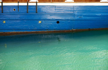 Emerald water is under blue board of boat.
