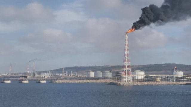 Flare stack  and smoke of petrochemical refinery on sea shore