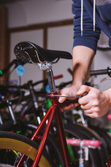 Theme repair bikes. Close-up of a Caucasian man's hand use a hand tool Hex keys to adjust and install the silver color Seat Posts on a red bicycle