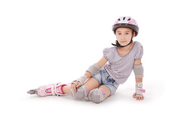 Happy little girl with roller skates and protective gear resting.