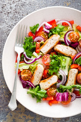 Healthy vegetable salad with grilled chicken breast, fresh lettuce, cherry tomatoes, red onion and pepper