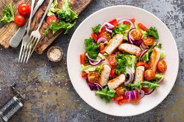 Healthy vegetable salad with grilled chicken breast, fresh lettuce, cherry tomatoes, red onion and...