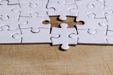 the unexpected solution, white jigsaw/puzzle with one piece at wrong position, over  black wooden...