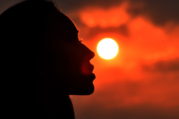 Silhouette of female face on sunset background