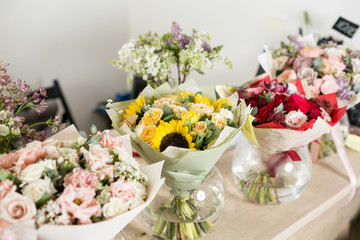 Obraz na płótnie Canvas Bouquets on table, florist business. Different varieties fresh spring flowers. Delivery service. Flower shop concept.