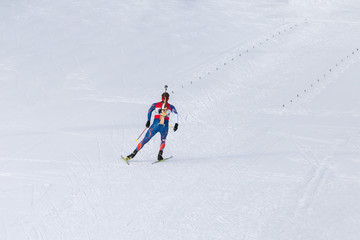 Biathlon racing, biathlete skiing with rifle on his back