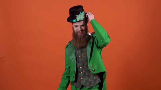 Young man leprechaun celebrating saint patrick's day isolated on orange wall walking in and away backwards