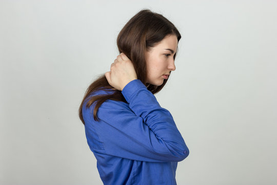 Portrait of a pretty woman holding her neck in pain and discomfort  standing over gray background