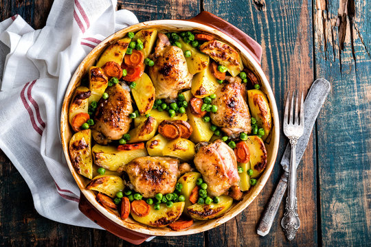 Chicken thighs baked with potato, carrot and green peas