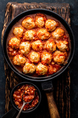 Homemade meatballs stewed in tomato sauce in cast iron pan