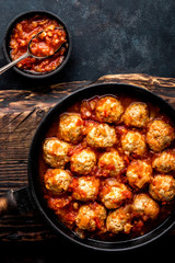 Homemade meatballs stewed in tomato sauce in cast iron pan
