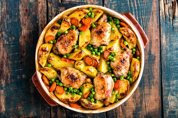 Chicken thighs baked with potato, carrot and green peas