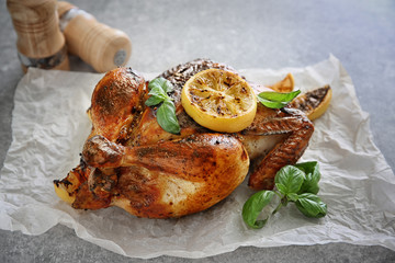 Delicious whole roasted chicken with lemon and basil on table