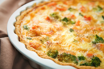 Baking dish with tasty broccoli quiche on table, closeup