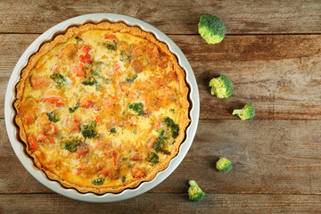 Baking dish with tasty broccoli quiche on table