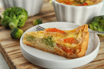 Plate with tasty broccoli quiche on wooden board