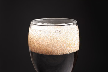 Glass of refreshing cola on black background, closeup