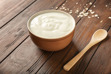 Tasty yogurt in dish on wooden table