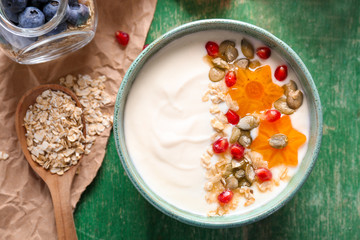 Yogurt with fruits and oat flakes in dish on wooden table