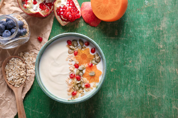 Yogurt with fruits and oat flakes in dish on wooden table