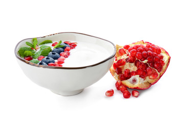 Yogurt with blueberry and pomegranate seeds in dish on white background