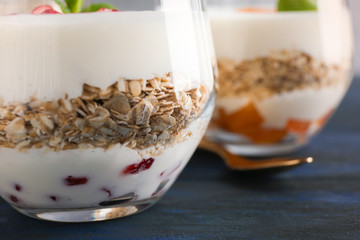 Yogurt with oat flakes in glass on wooden table