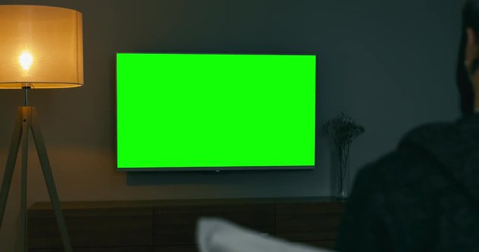 GREEN SCREEN Back view of Caucasian male sitting on sofa, watching sport basketball game on a TV screen. 4K UHD