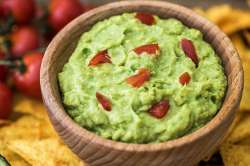 Guacamole in Wooden Bowl with Tortilla Chips and Ingredients