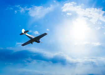 Fototapeta na wymiar sports plane flies in a blue cloudy sky