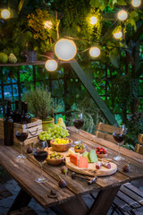 Garden table with cheese, red wine in the garden