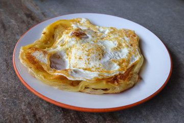 Roti canai with egg  on the plate over dining table