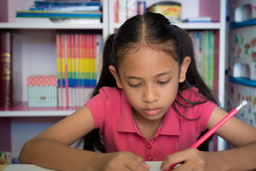 Little girl doing homework on table at home.