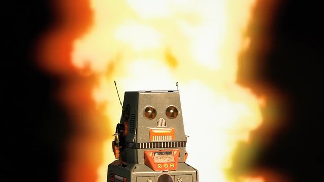 A tin toy robot standing still while something explodes behind it. Doomsday Apocalypse concept.

