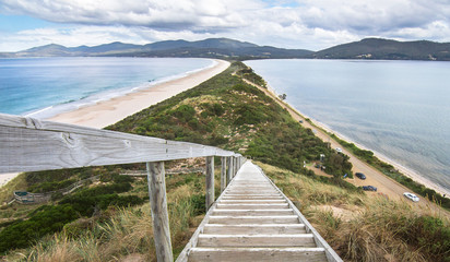 Looking down a staircase at a very narrow isthmus with a road along it on Bruny Island, Tasmania.