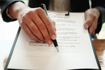 Real estate agent with hand putting signing contract,have a contract in place to protect it,signing of modest agreements form in office.Concept real estate,moving home or renting property